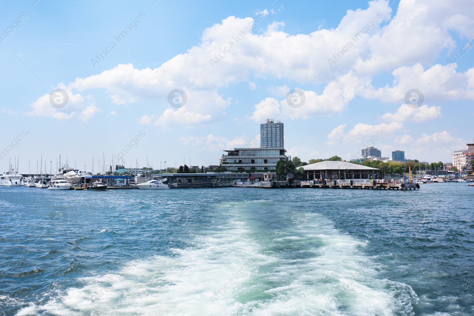 Photo of Boat track on sea surface and beautiful view of city on shore