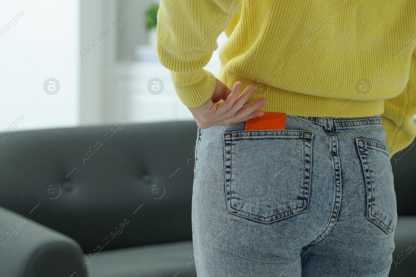 Photo of Woman pulling condom out of pocket indoors, closeup and space for text. Safe sex