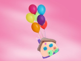 Image of Many balloons tied to playdough house flying on pink background