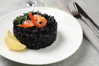 Photo of Delicious black risotto with shrimps and lemon on marble table, closeup