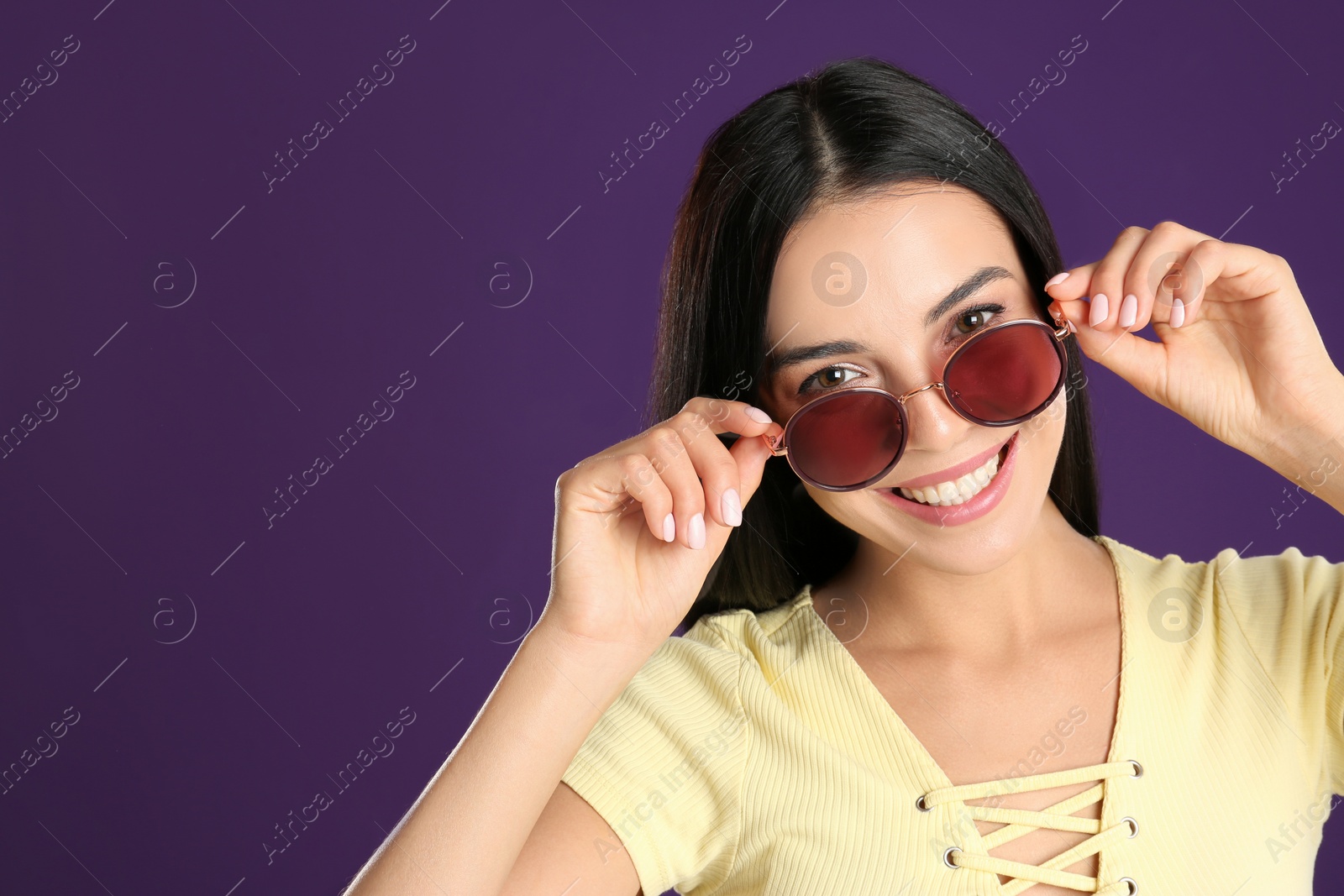 Photo of Beautiful woman wearing sunglasses on purple background. Space for text