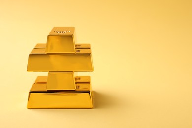 Photo of Stack of shiny gold bars on yellow background. Space for text
