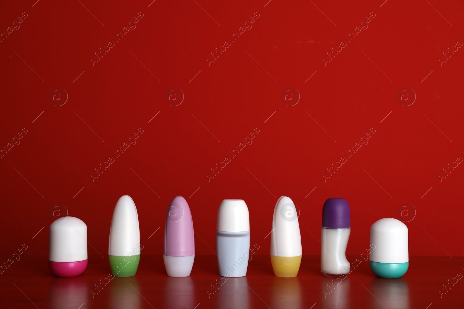 Photo of Different deodorants on table against red background. Space for design