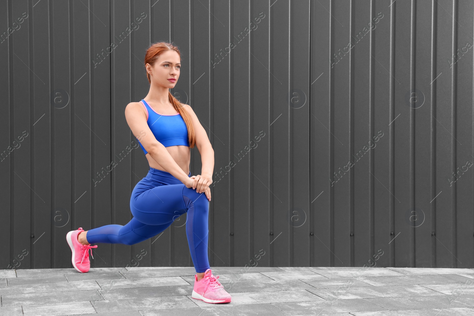 Photo of Beautiful woman in gym clothes doing exercises on street, space for text