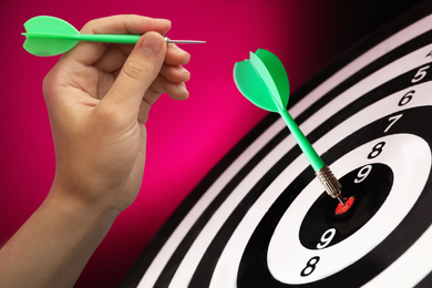 Woman with darts and board on red background, closeup
