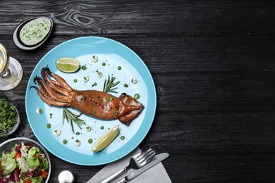 Photo of Delicious grilled squid served on black wooden table, flat lay. Space for text