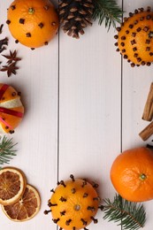 Photo of Pomander balls made of tangerines with cloves, spices and fir branches on white wooden table, flat lay. Space for text