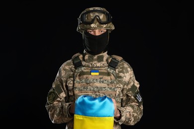 Photo of Soldier in military uniform with Ukrainian flag on black background