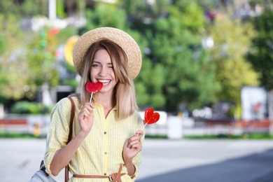 Photo of Beautiful smiling woman biting candy on city street