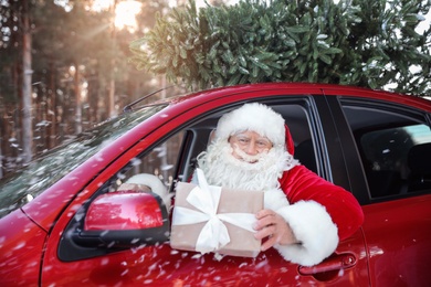 Photo of Authentic Santa Claus in car with gift box, view from outside