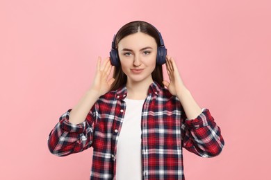 Woman in headphones enjoying music on pink background