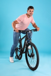 Photo of Handsome young man with modern bicycle on light blue background