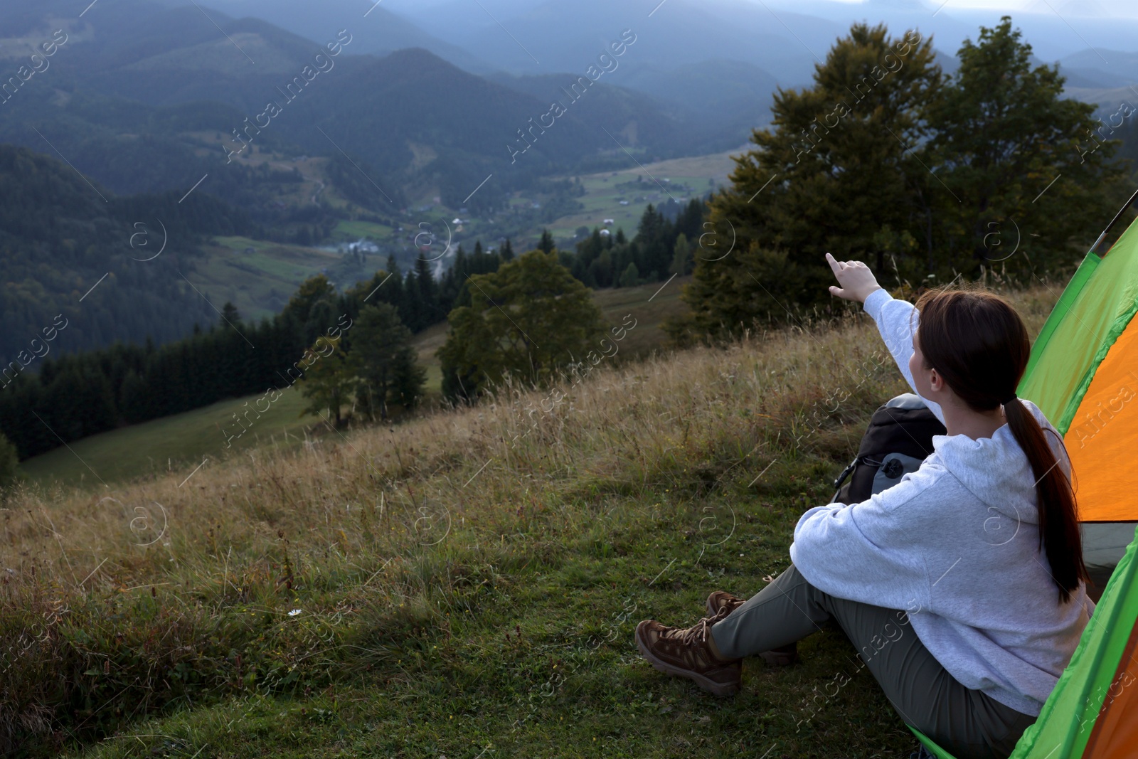 Photo of Tourist with camping tent sitting on hill in mountains