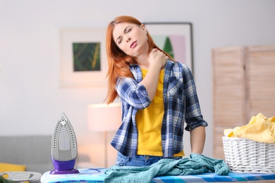 Tired housewife ironing clothes at home