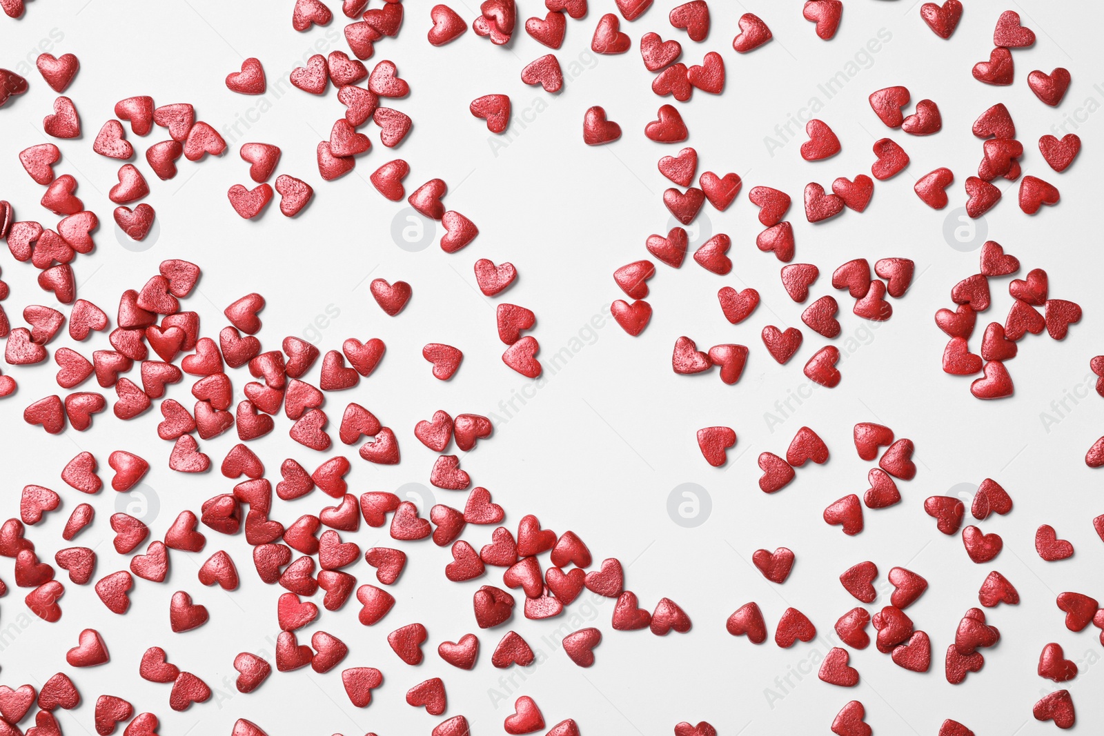 Photo of Bright heart shaped sprinkles on white background, flat lay