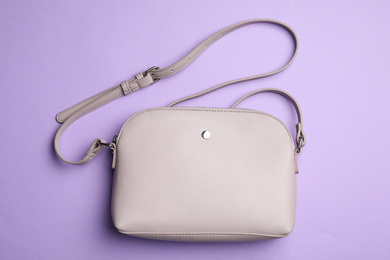 Stylish woman's bag on violet background, top view