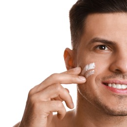 Photo of Handsome man applying face cream on white background, closeup