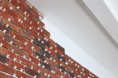 Photo of Decorative bricks with tile leveling system on white wall in repaired room