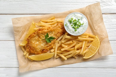 Photo of British traditional fish and potato chips on wooden background, top view