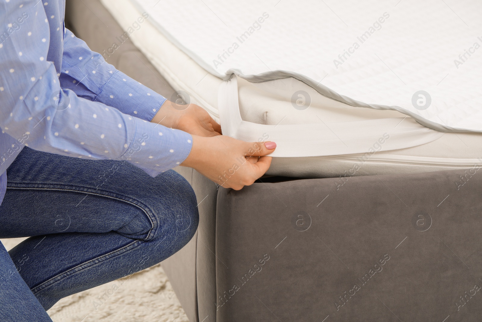 Photo of Woman putting cover on mattress indoors, closeup