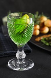 Photo of Delicious drink with tarragon in glass on dark textured table