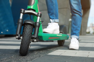 Photo of Woman with modern electric kick scooter outdoors, closeup