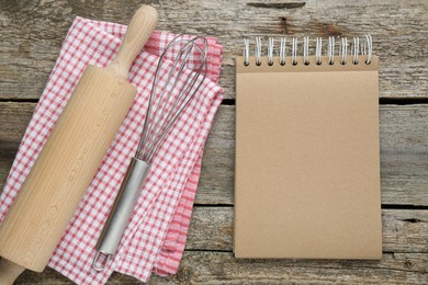 Blank recipe book and kitchen utensils on old wooden table, flat lay. Space for text