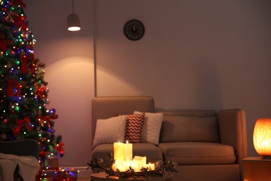 Photo of Stylish room interior with candles and decorated Christmas tree