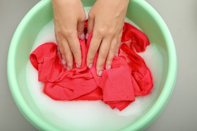 Photo of Woman washing color clothes in basin, closeup