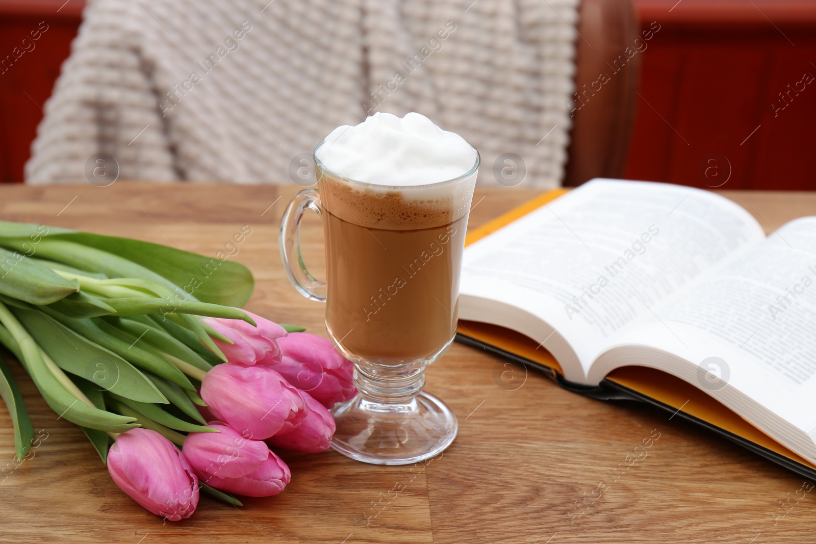 Photo of Glass of delicious cocoa, pink tulips and book on wooden table