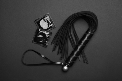 Photo of Whip and condoms on black background, top view. Sex game