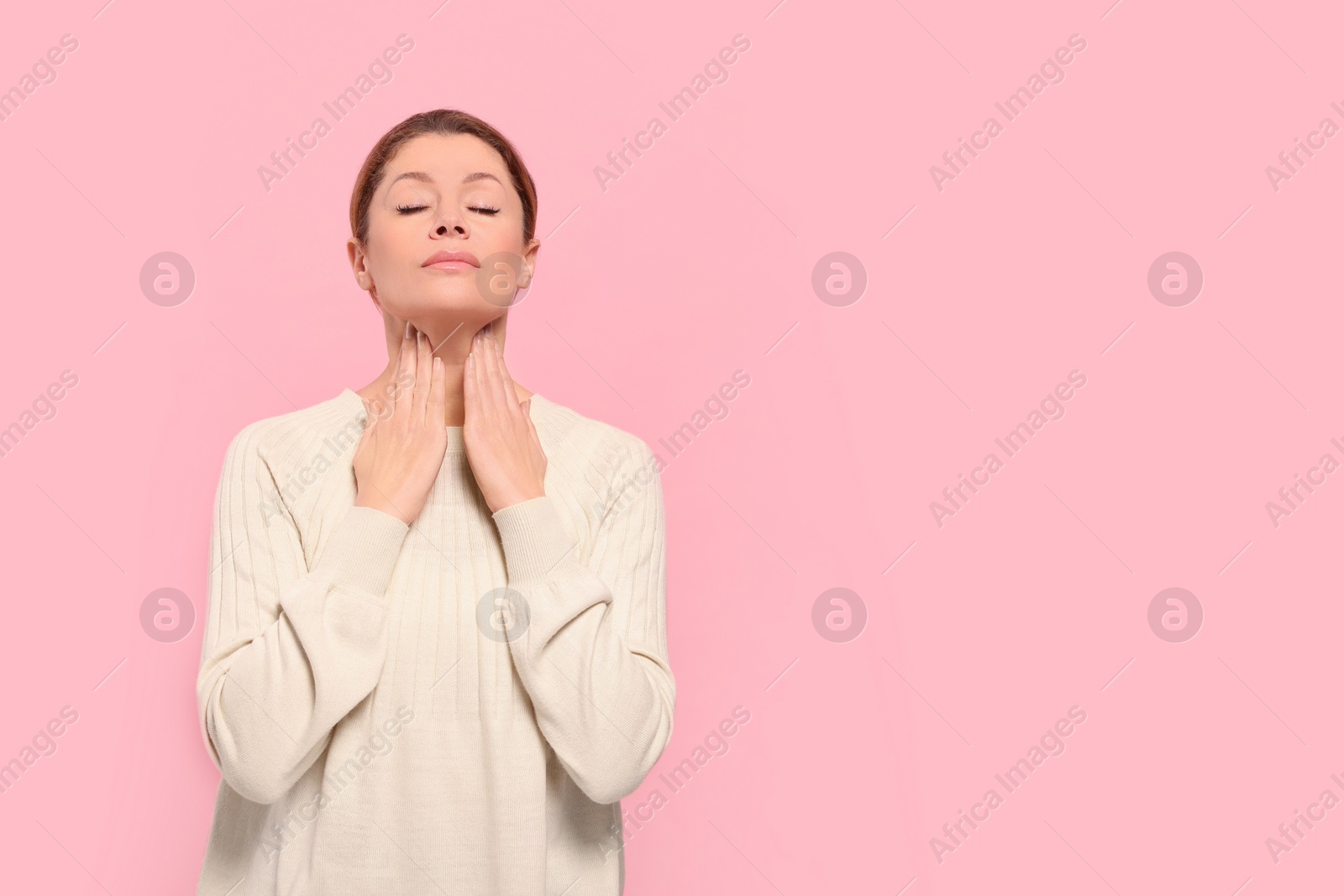 Photo of Woman suffering from sore throat on pink background. Space for text