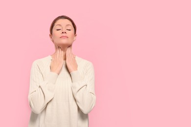 Photo of Woman suffering from sore throat on pink background. Space for text