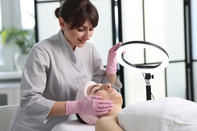 Cosmetologist making face massage to client in clinic