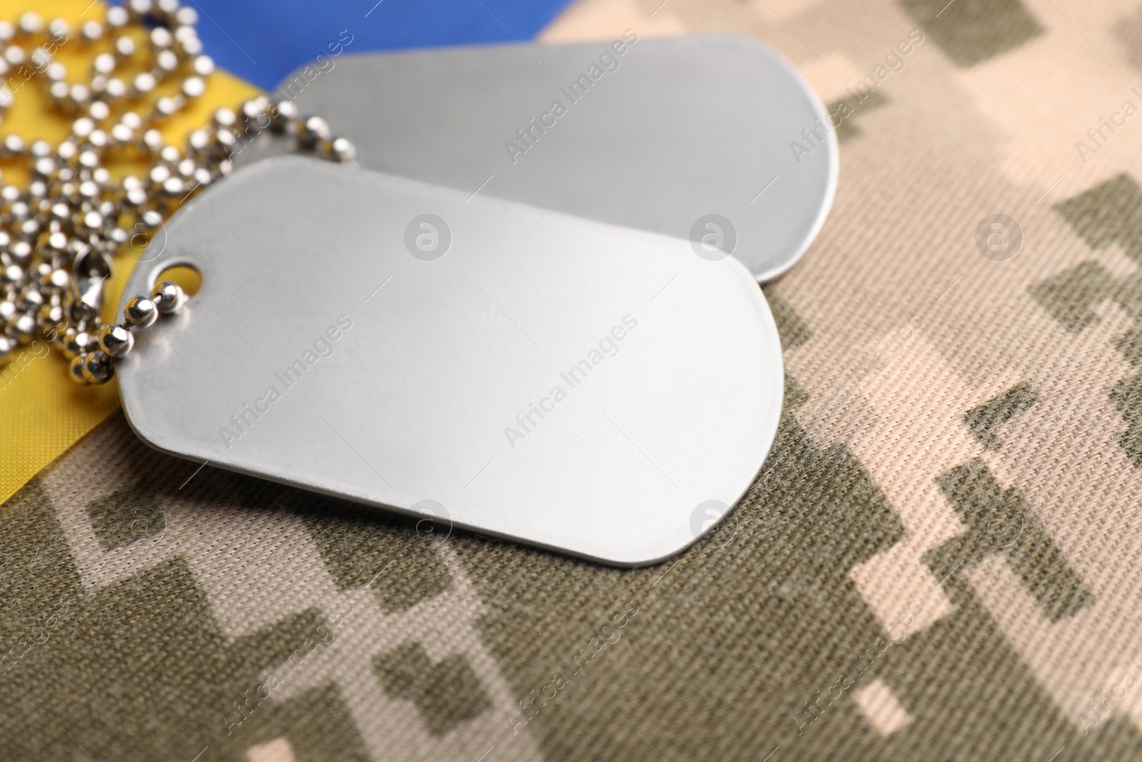 Photo of Military ID tags and Ukrainian flag on pixel camouflage, closeup