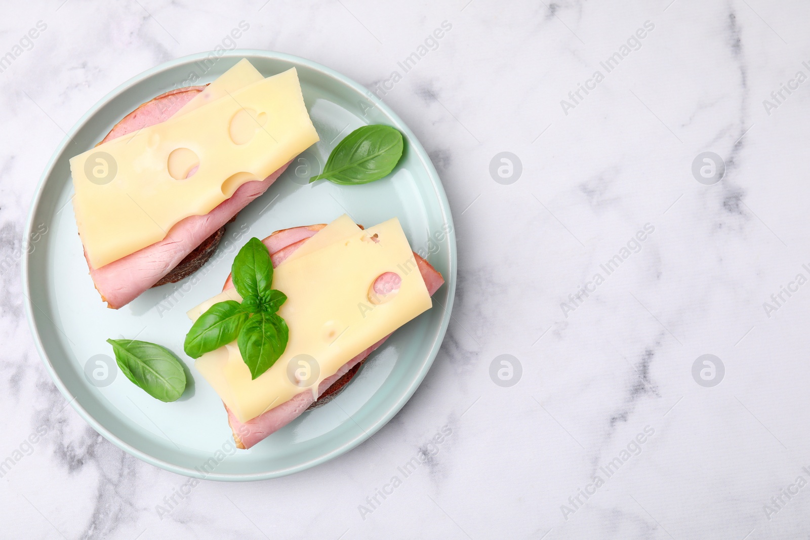 Photo of Delicious sandwiches with ham and cheese on white marble table, top view. Space for text