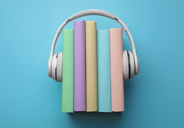 Photo of Books and modern headphones on light blue background, top view