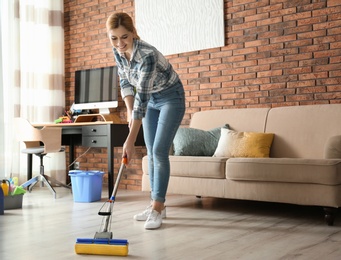 Woman cleaning floor with mop in living room