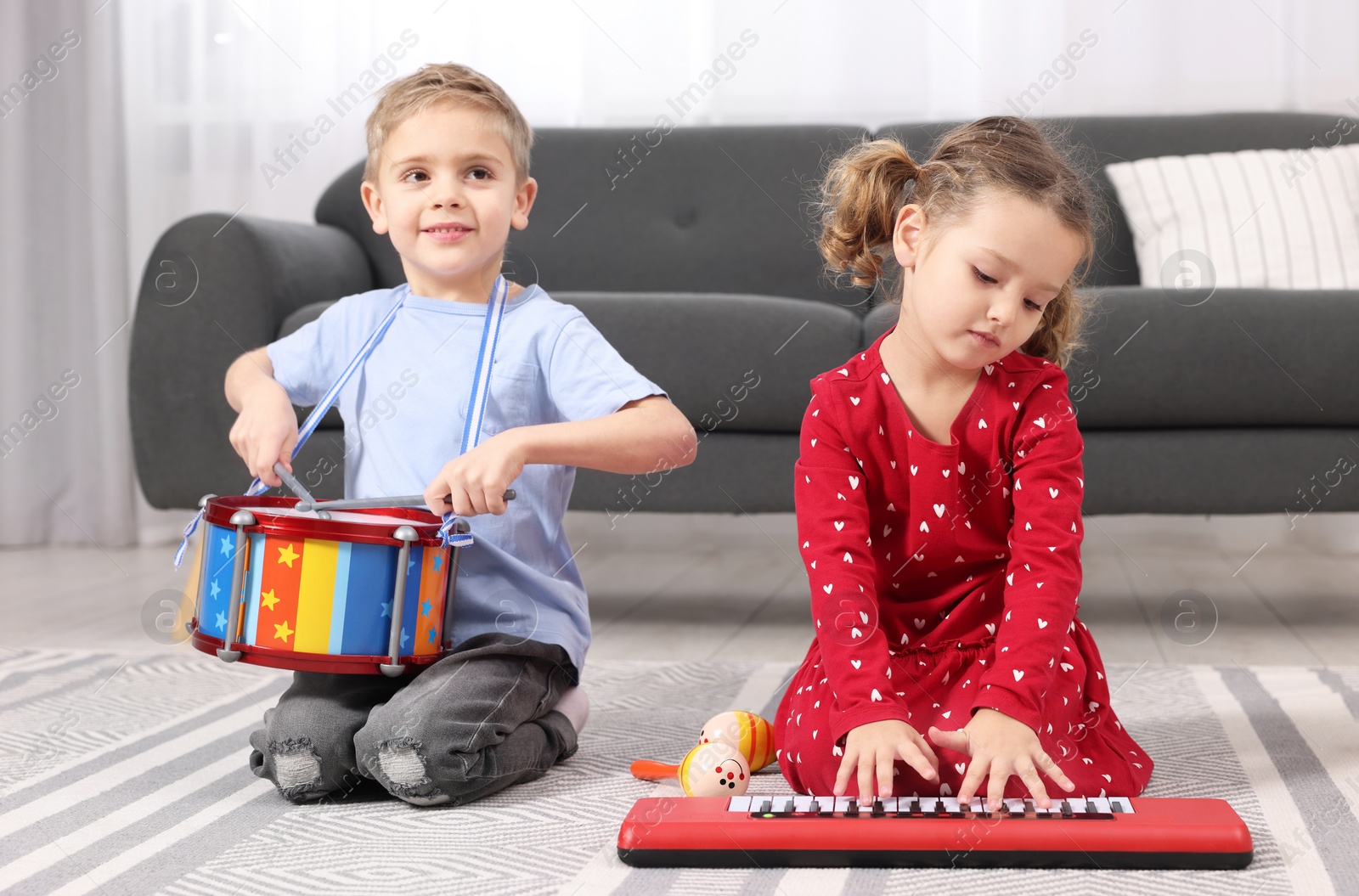 Photo of Little children playing toy musical instruments at home