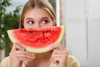 Photo of Beautiful teenage girl with slice of watermelon indoors