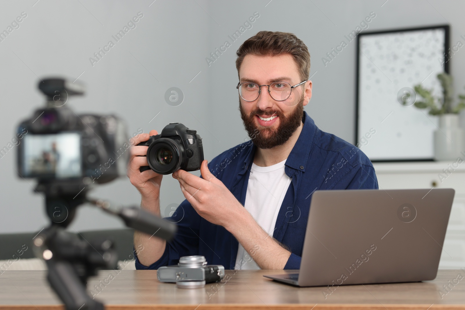 Photo of Smiling technology blogger recording video review about cameras at home