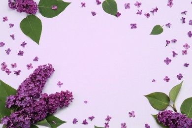 Photo of Frame of beautiful lilac flowers and green leaves on pale purple background, flat lay. Space for text