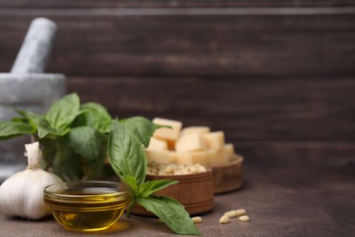 Photo of Different ingredients for cooking tasty pesto sauce on brown textured table, closeup. Space for text