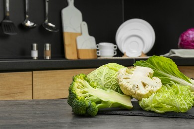 Different types of cut cabbage on grey table in kitchen, space for text