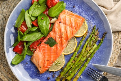 Photo of Tasty grilled salmon with tomatoes, asparagus, spinach and lemon served on table, top view