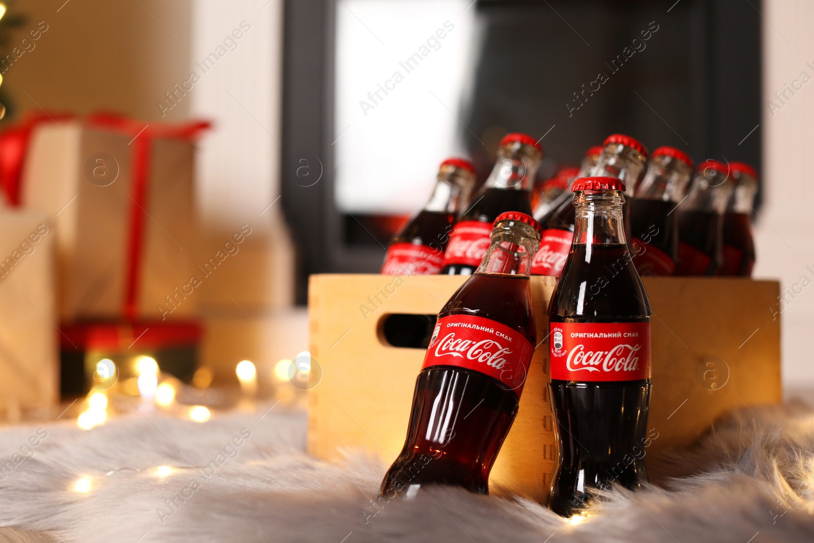 Photo of MYKOLAIV, UKRAINE - JANUARY 18, 2021: Wooden 
 crate with Coca-Cola bottles on floor in room