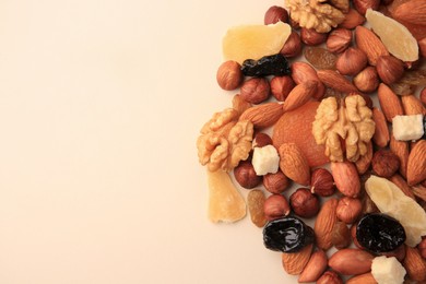Photo of Different tasty nuts and dried fruits on beige background, flat lay. Space for text