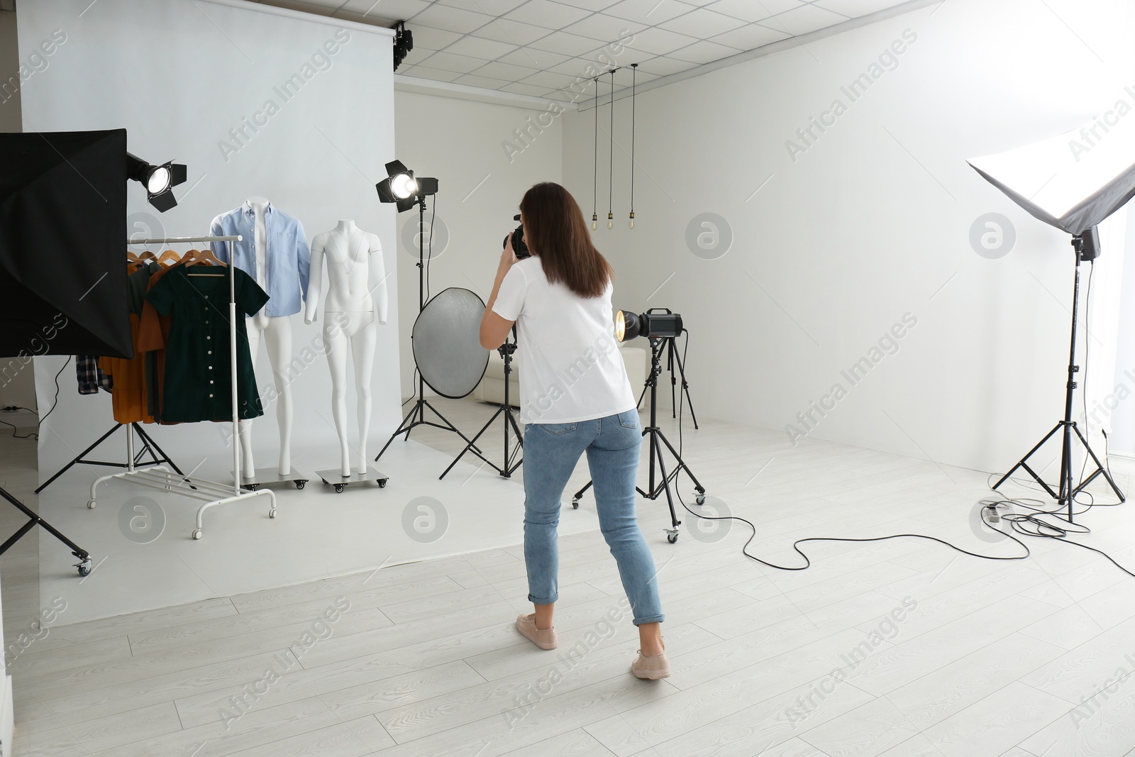 Photo of Professional photographer taking picture of ghost mannequins with modern clothes in photo studio