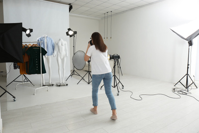 Professional photographer taking picture of ghost mannequins with modern clothes in photo studio