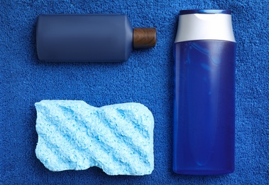 Photo of Bottles and bast wisp on blue towel, flat lay. Men's cosmetics
